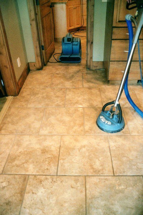 A vacuum cleaner is sitting on a tiled floor next to a fan.
