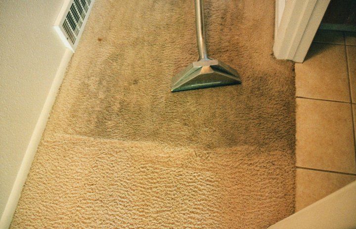 A vacuum cleaner is cleaning a dirty carpet in a room.
