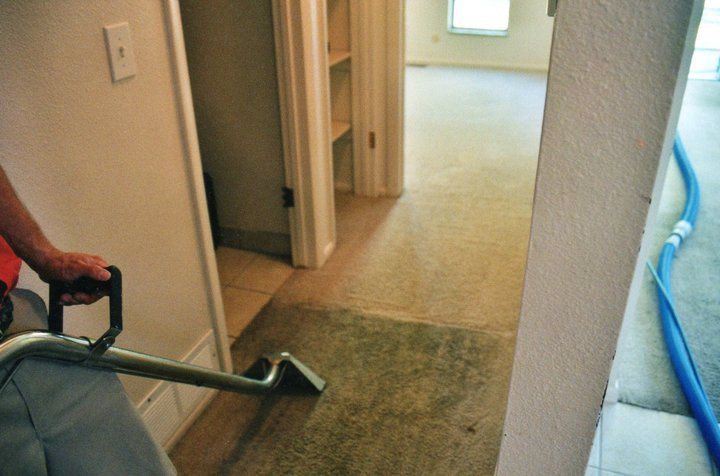 A person is using a vacuum cleaner to clean a carpet in a hallway.