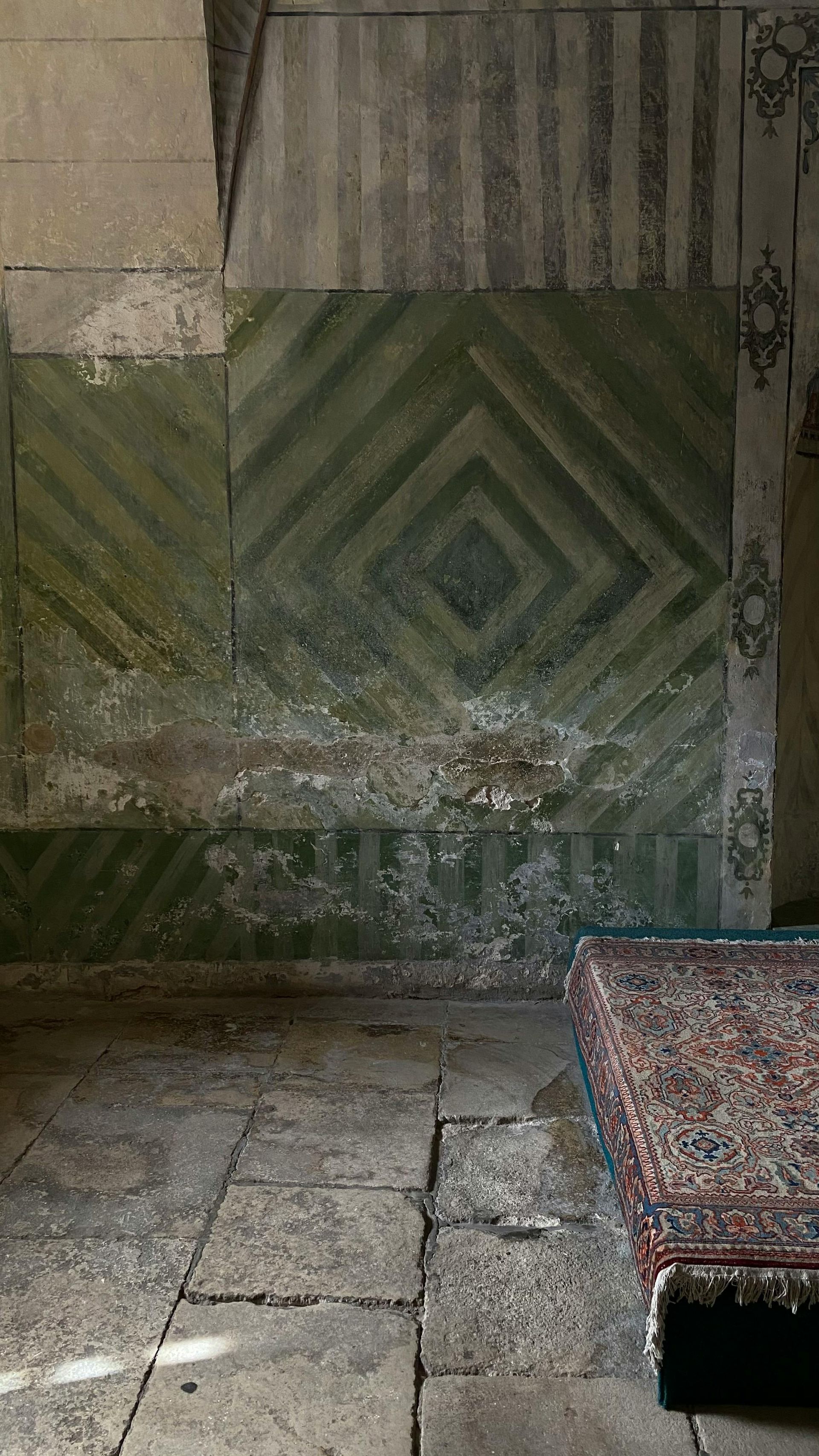 There is a rug on the floor in front of a wall with a pattern on it.