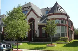 White pickup truck towing a black dump trailer on a grassy field under a blue sky.
