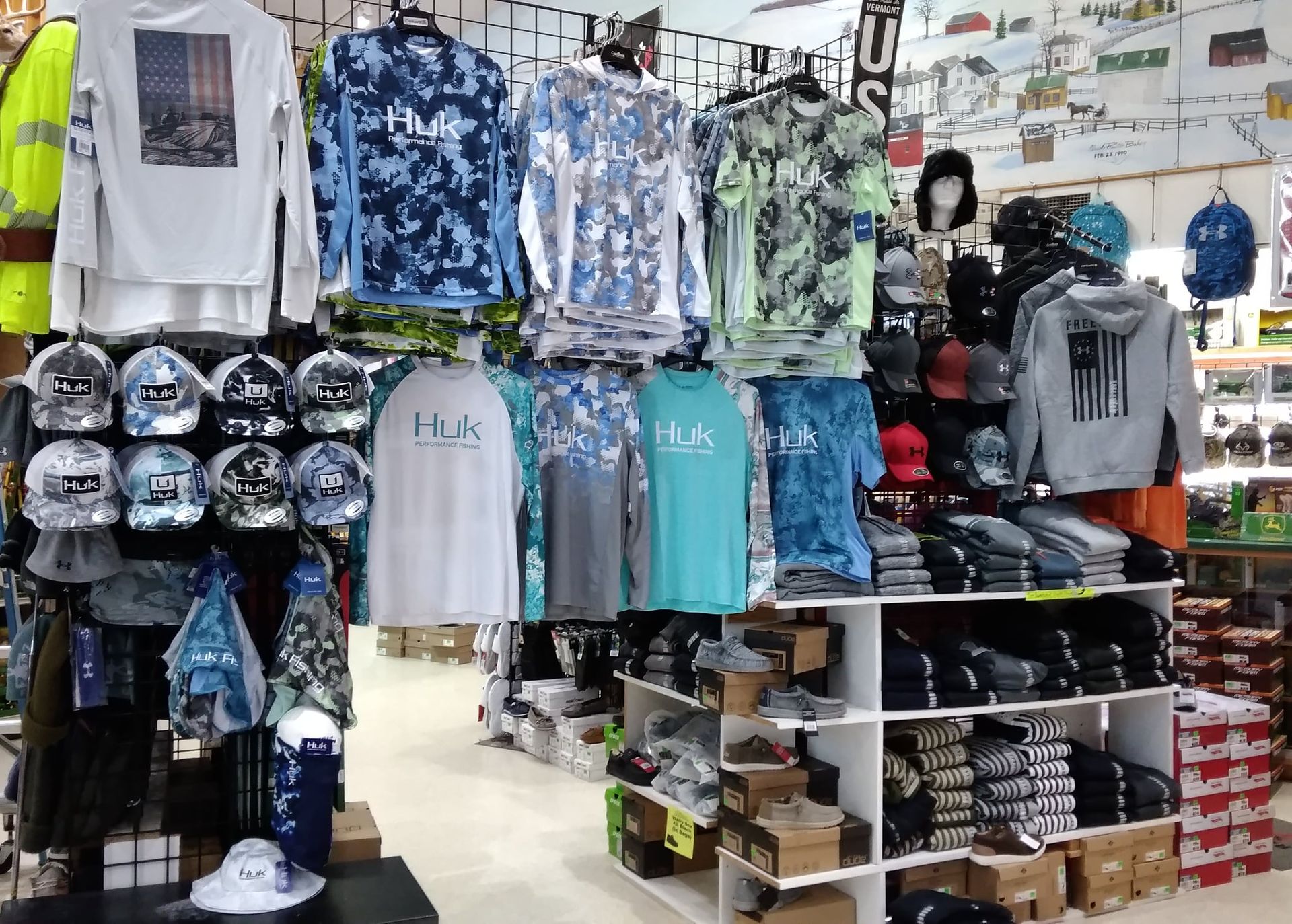 Clothing store interior with shirts, hats, and other merchandise displayed on racks and shelves.