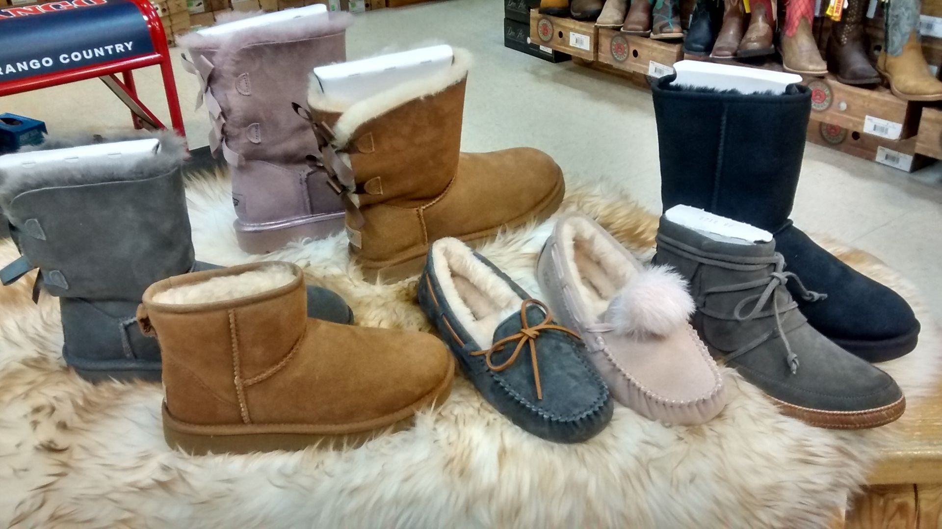 Assortment of UGG boots and slippers on display in a store setting, various colors and styles.
