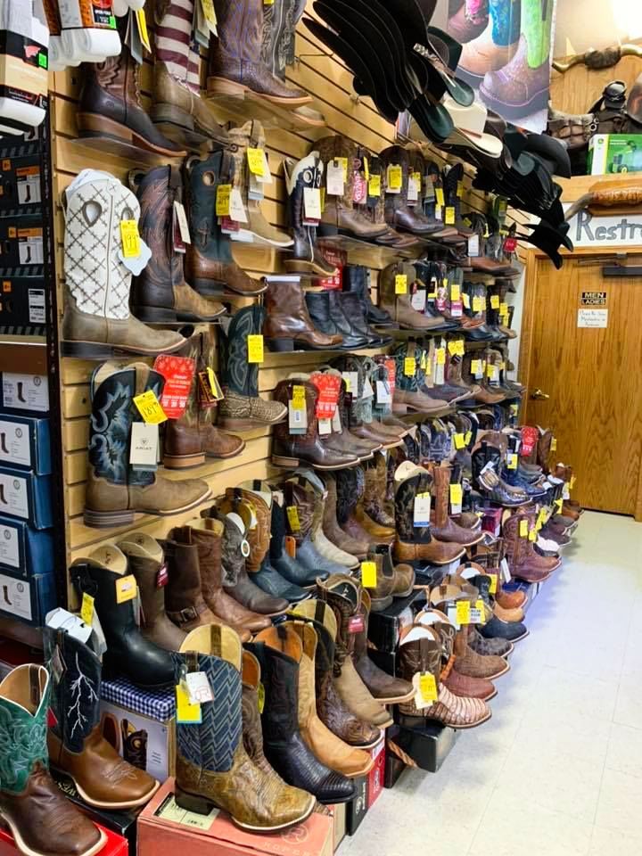 Wall of cowboy boots in a store. Many colors and styles displayed. Yellow price tags on each pair.