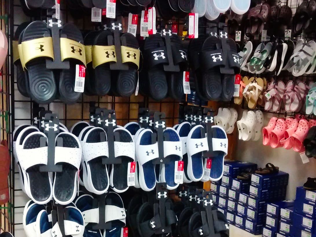 Display of Under Armour slides in various colors at a store.