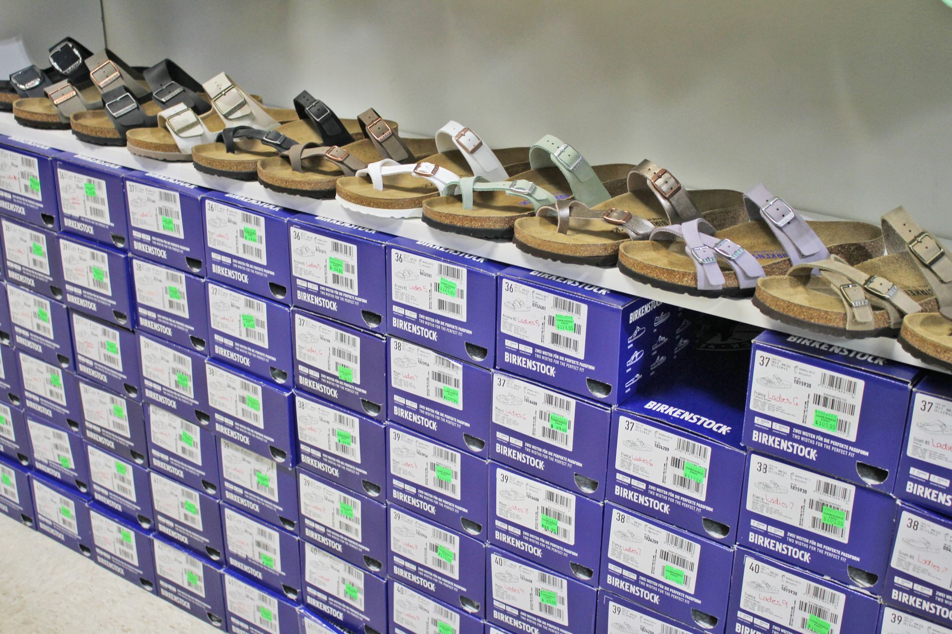 Sandals displayed on a wall of shoe boxes in a store.