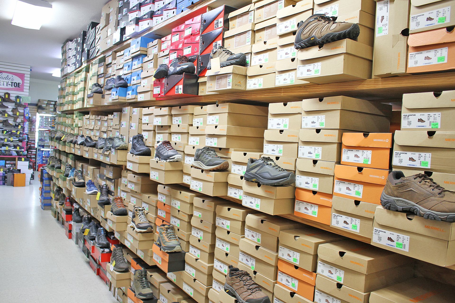 Shoe store interior with shelves of shoe boxes stacked, displaying various shoe styles on top.