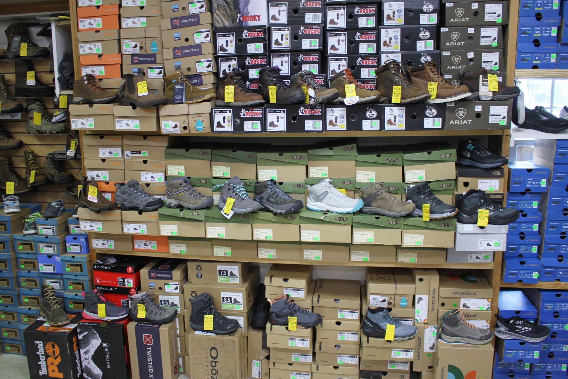 Shelves in a shoe store displaying numerous boxes of work boots and hiking shoes.