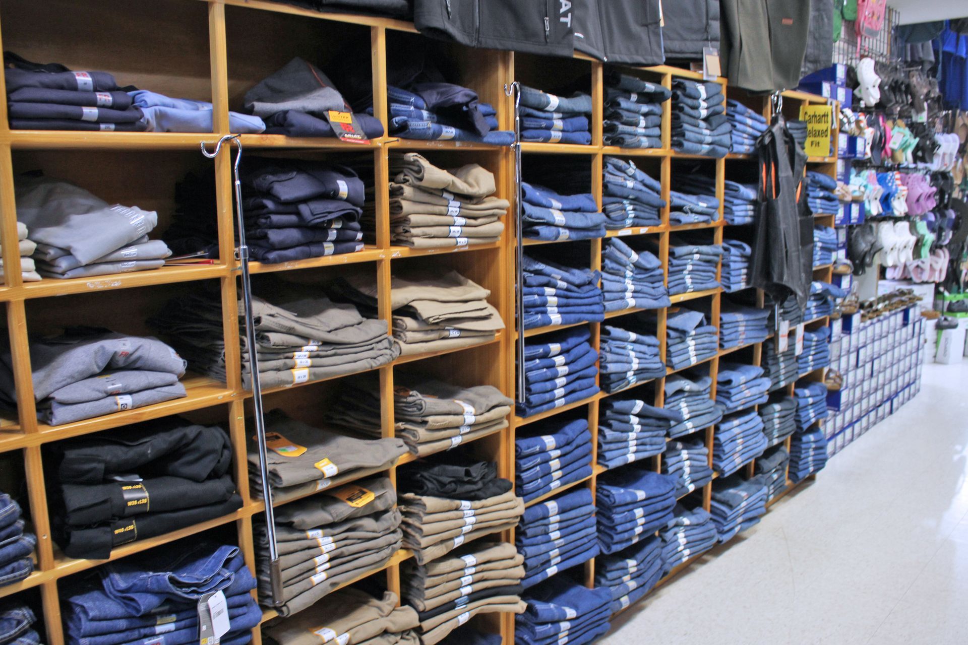 Shelves in a clothing store stocked with folded jeans and other garments, brown shelves, blue and khaki clothing.