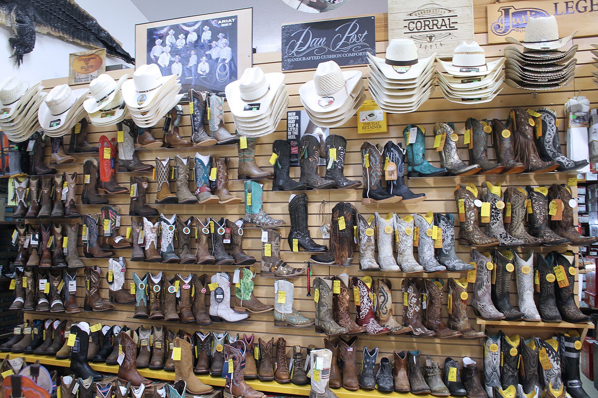 Wall display of cowboy boots and hats in a store.