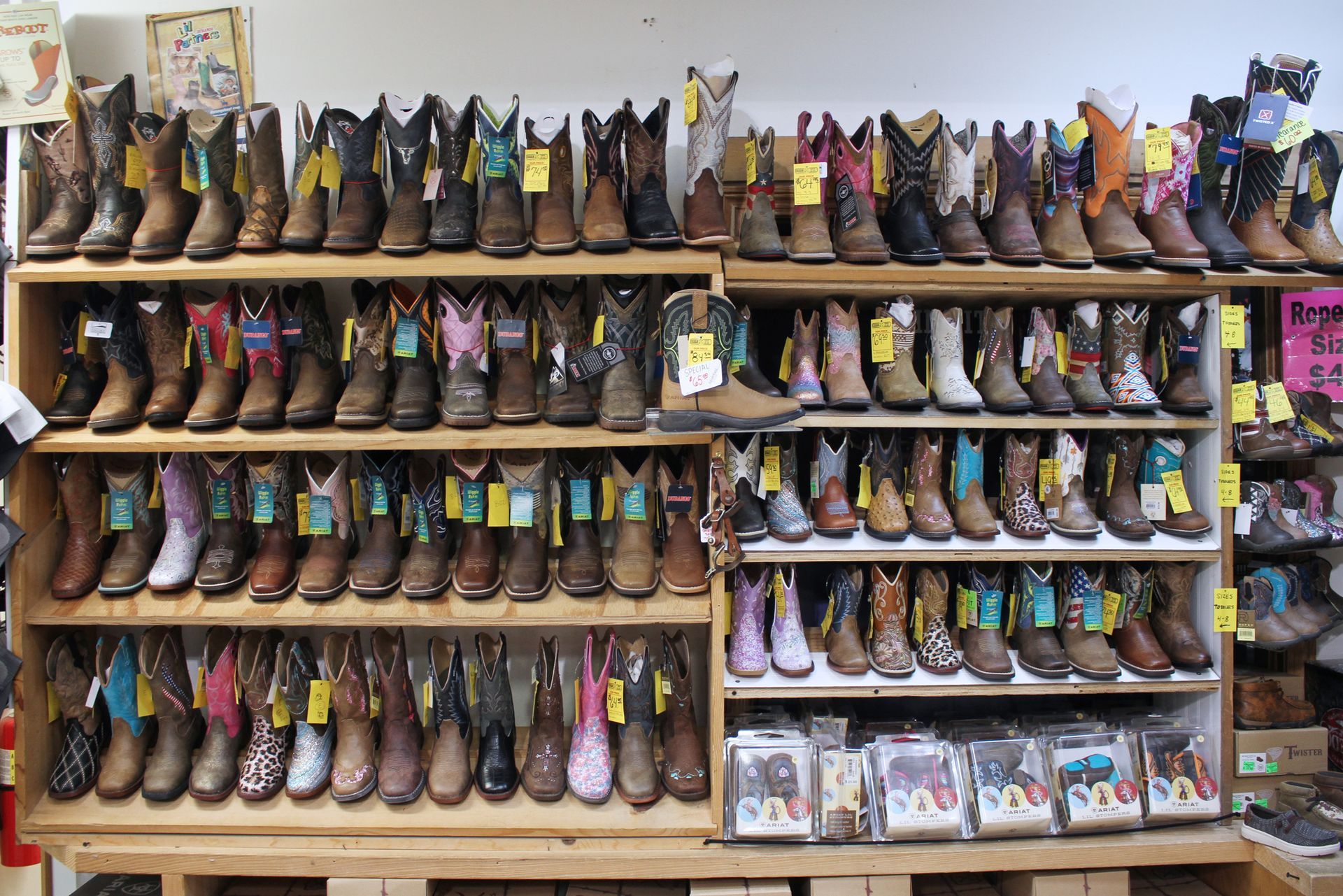 Shelves filled with various cowboy boots in a store; various colors and patterns visible.