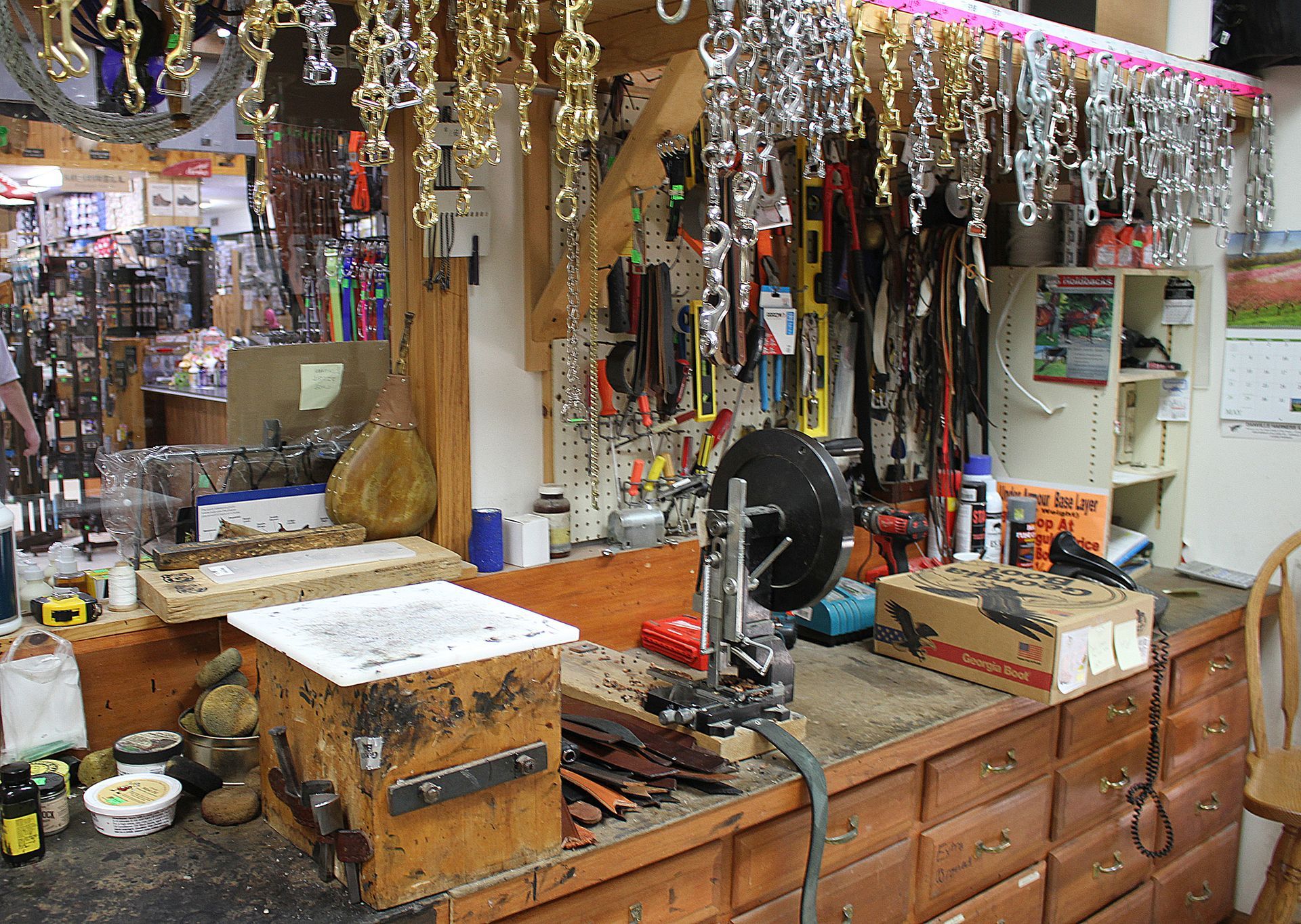 Interior of a workshop with tools, hardware, and equipment, likely for leatherwork or horse tack.