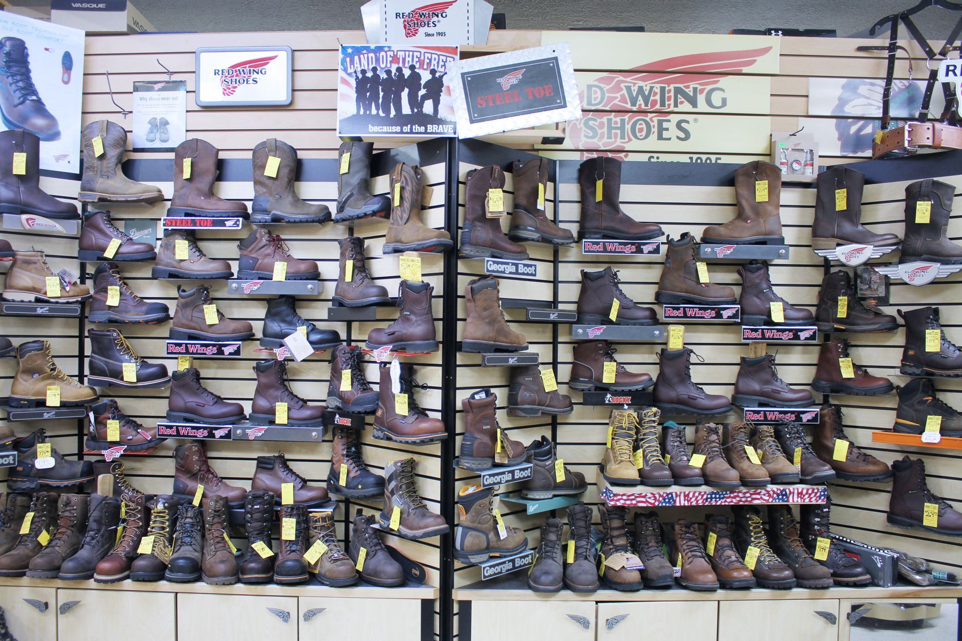 Rows of work boots on display at a shoe store, primarily brown.