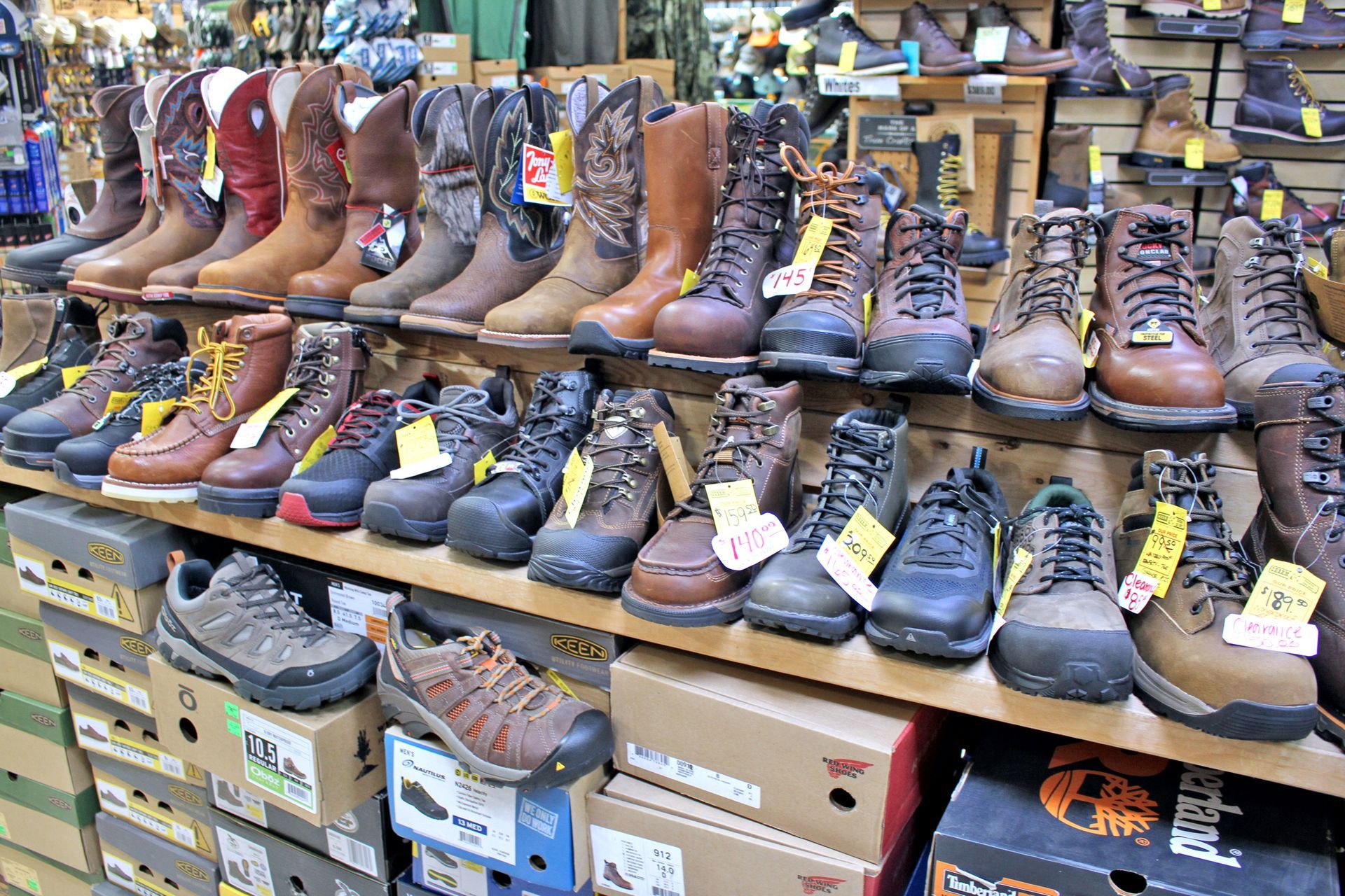 Rows of various work boots and shoes on display at a store.