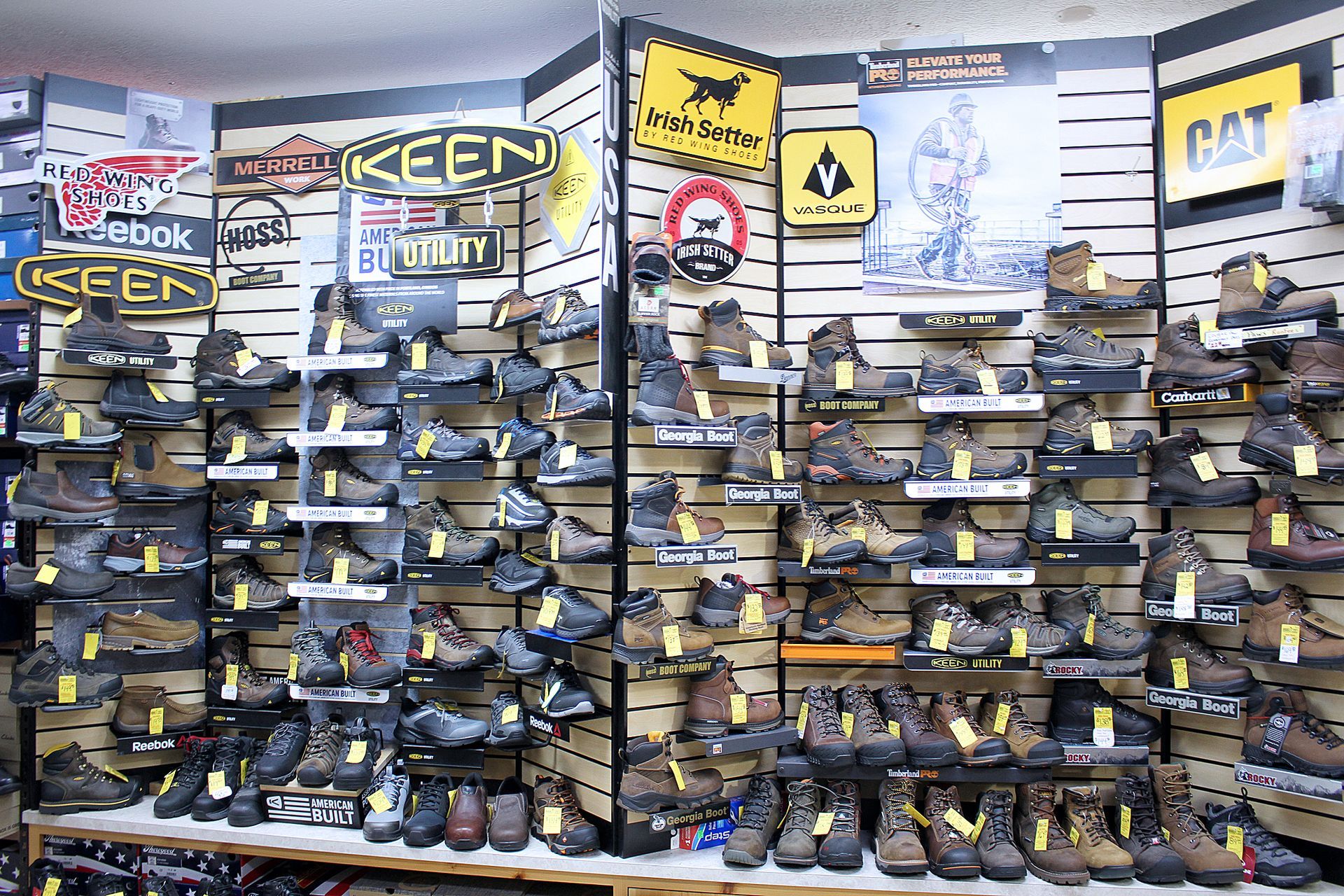 Shoe store interior displaying numerous work boots on shelves, featuring various brands.