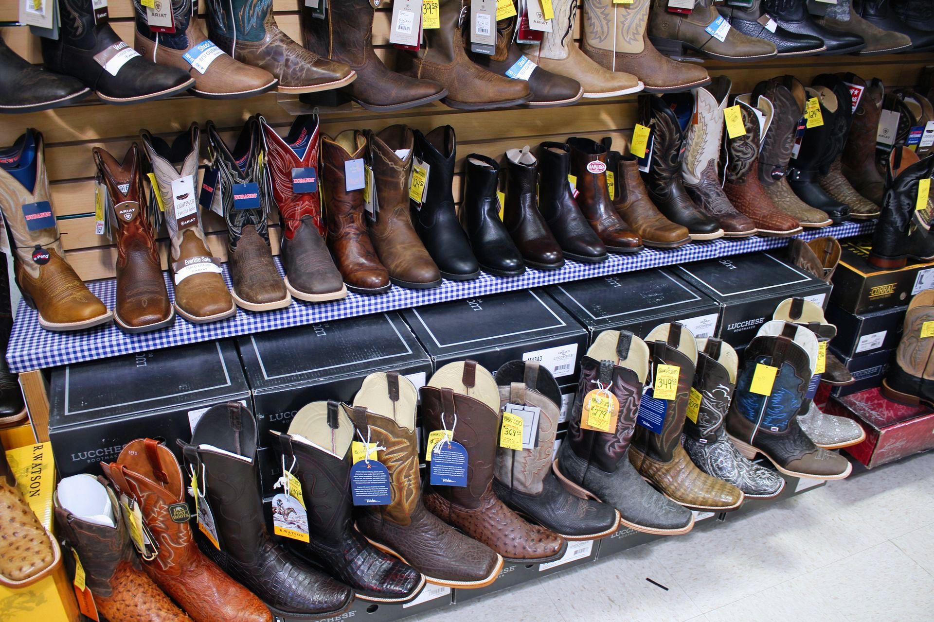 Rows of cowboy boots on shelves and boxes in a store.