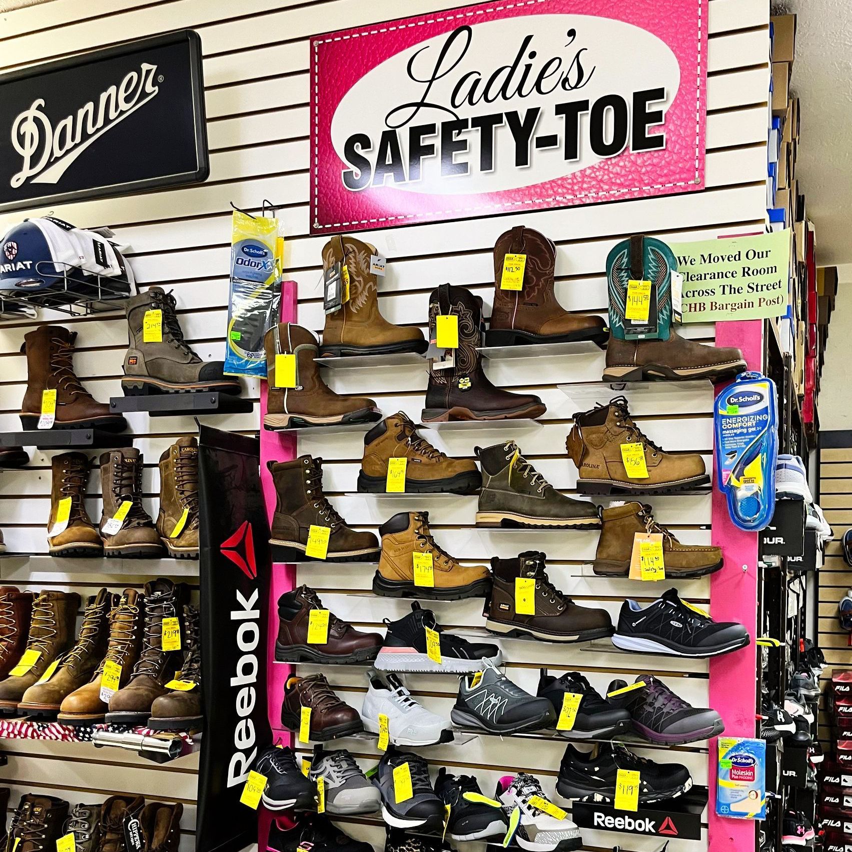 Display of various ladies' safety-toe work boots and shoes for sale in a store.