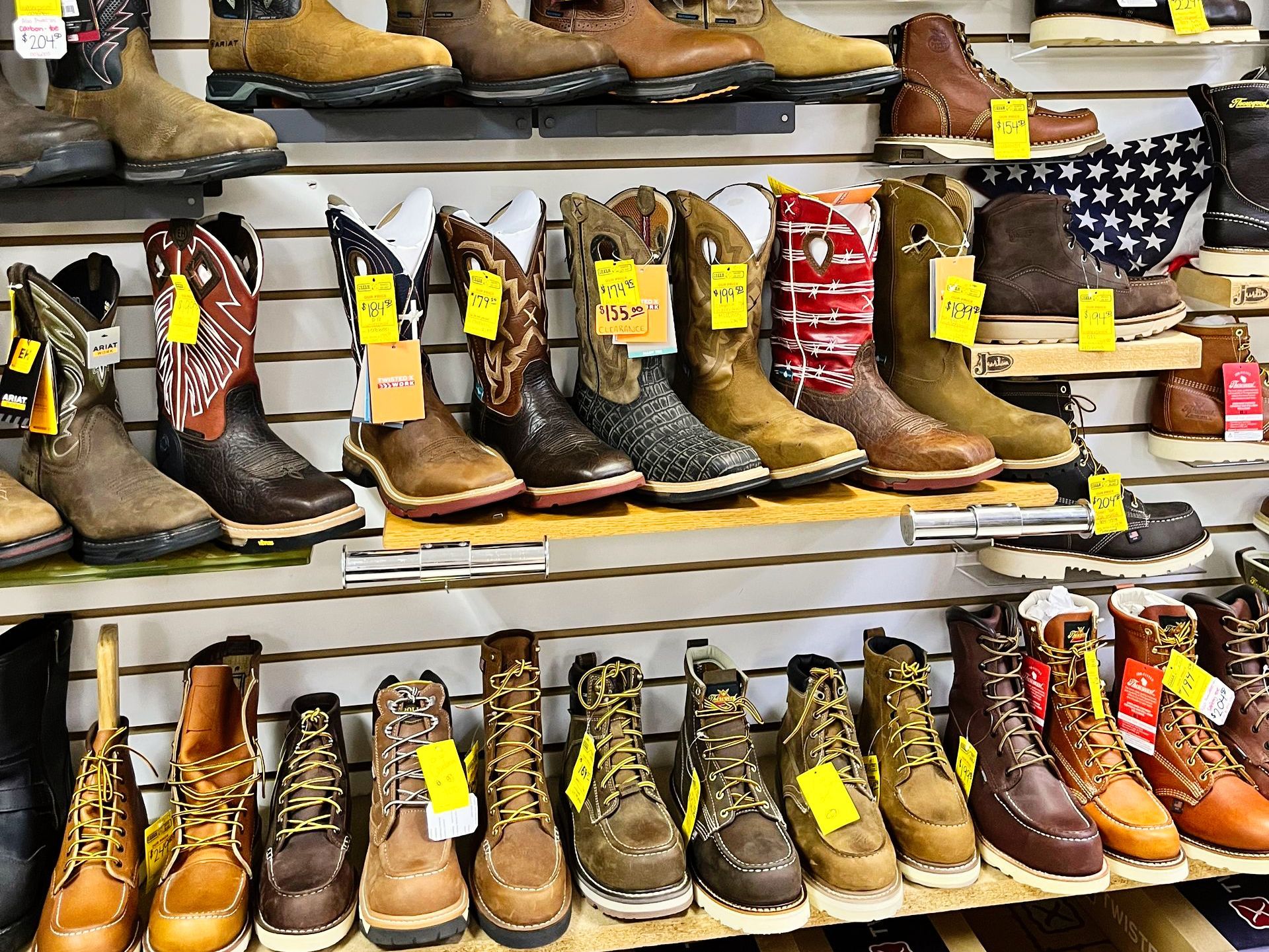 Rows of cowboy boots and work boots on display shelves in a store.