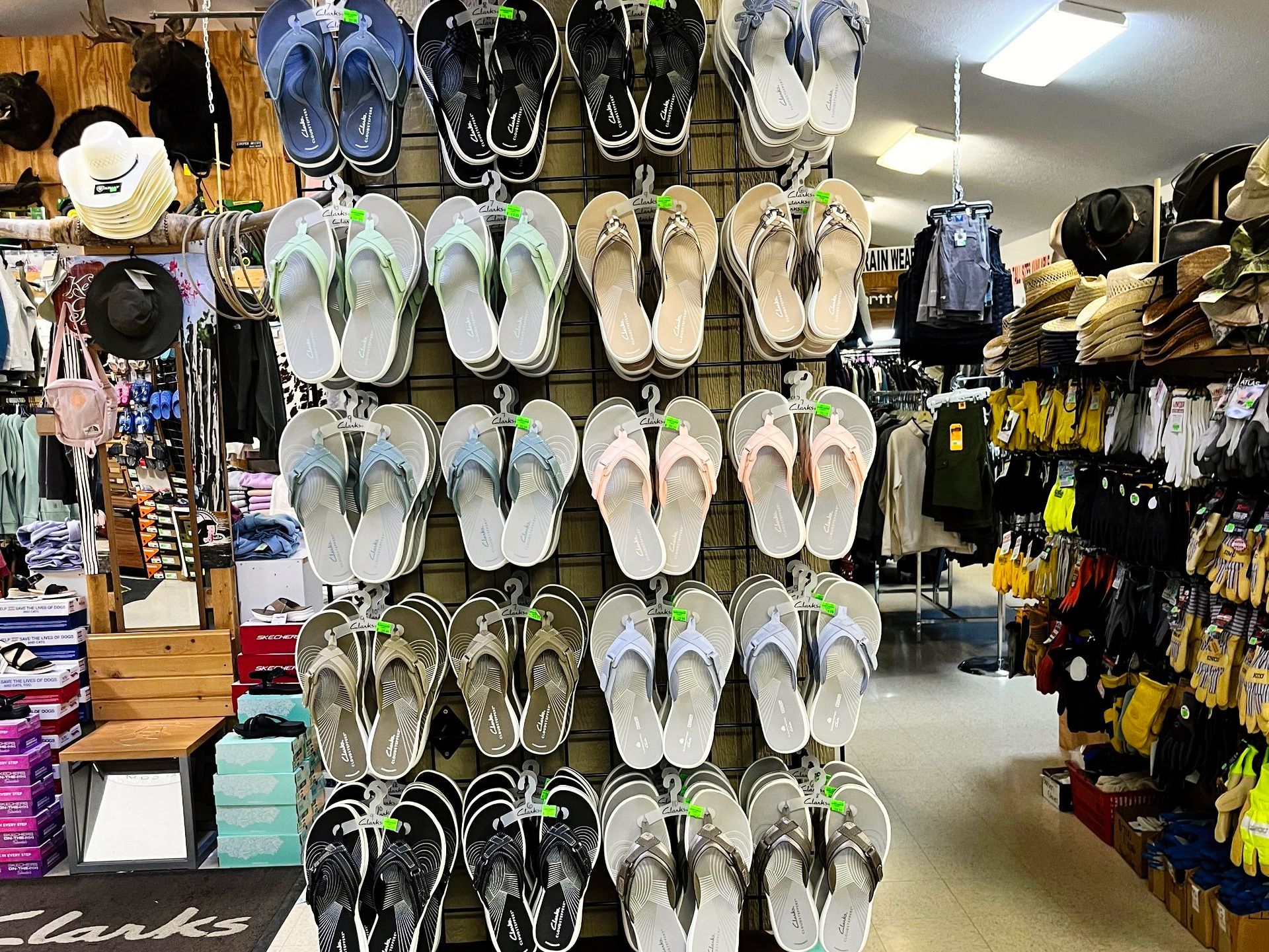 Flip-flops displayed on a metal rack in a retail store; other merchandise visible in the background.