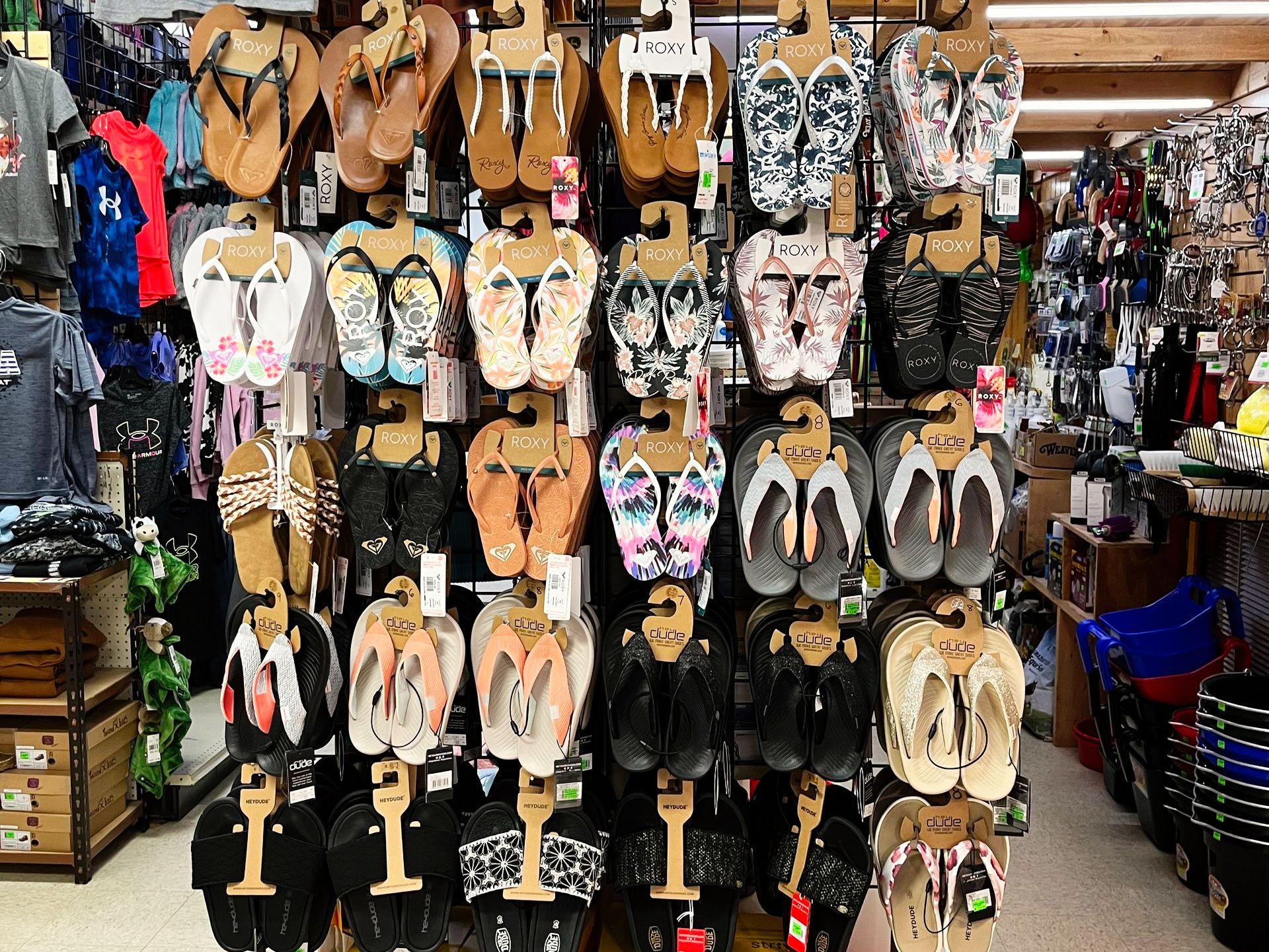Flip-flops on display at a store, various colors and styles, hanging on a grid.