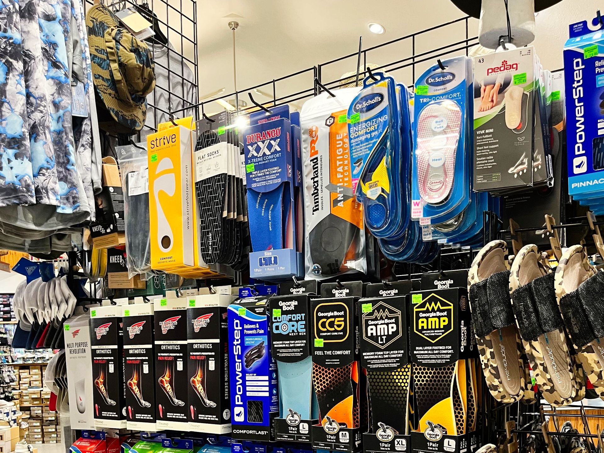 Shelves in a store filled with socks, insoles, and sandals, brightly lit with overhead lights.