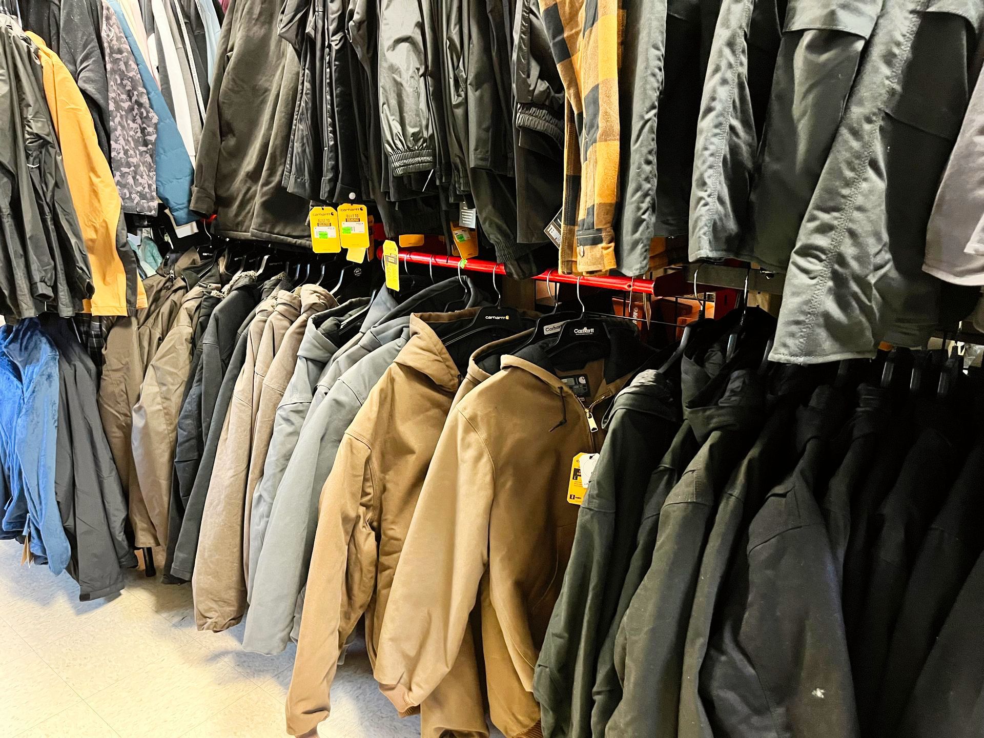 Jackets hanging on a clothing rack, varying colors including tan, gray, and black.