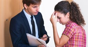 serious man explaining documents to worried woman in a doorway