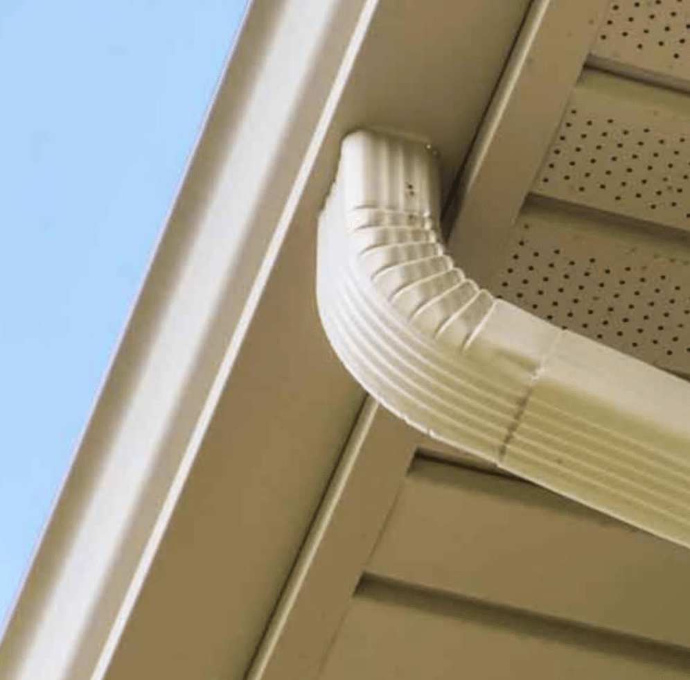 White gutter elbow directing water flow from a tan roof overhang.