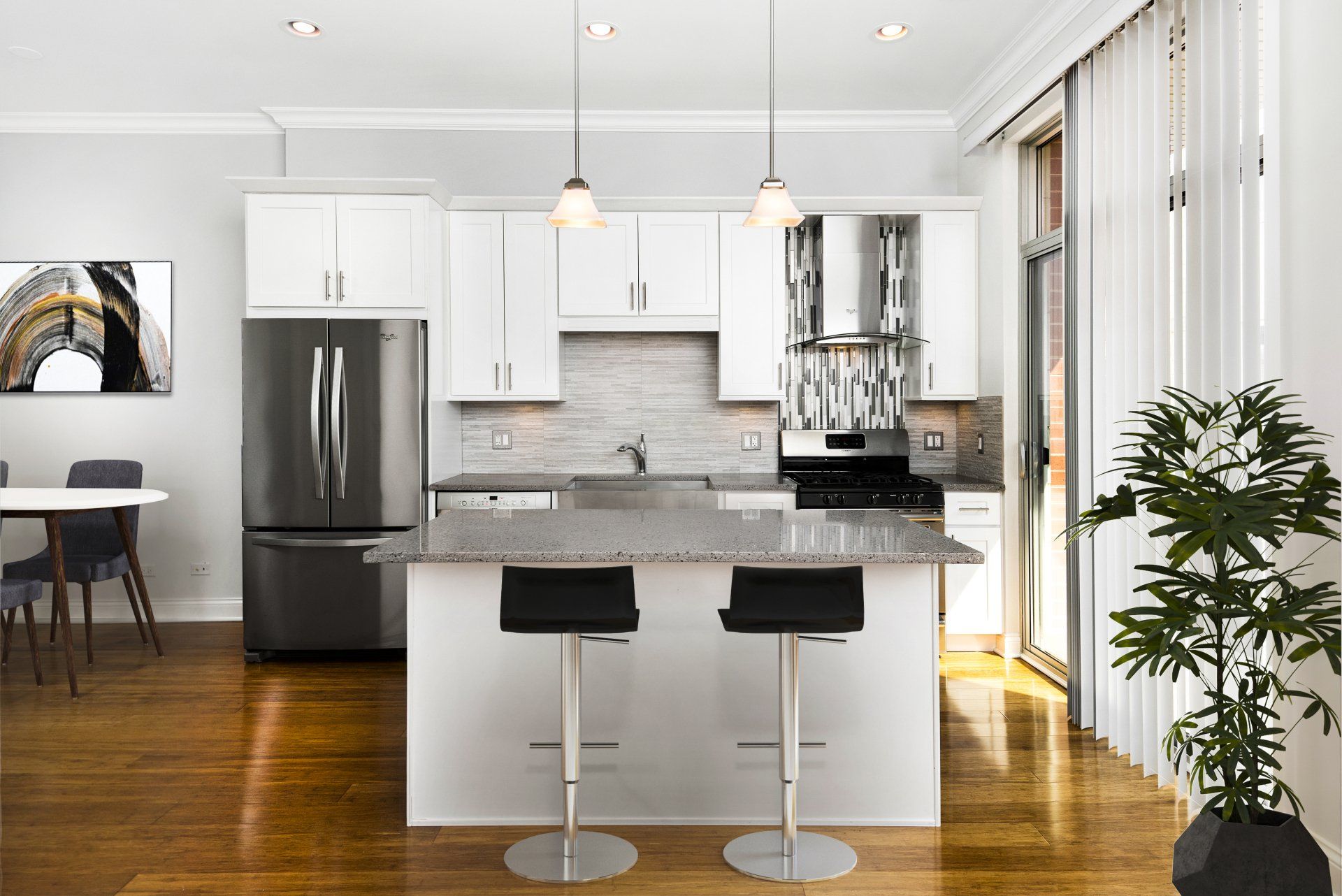 A kitchen with white cabinets, stainless steel appliances, and a large island at Reside on Jackson.