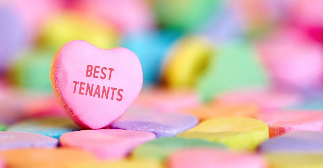 A heart shaped candy that says `` best tenants '' is sitting on top of a pile of candy hearts.