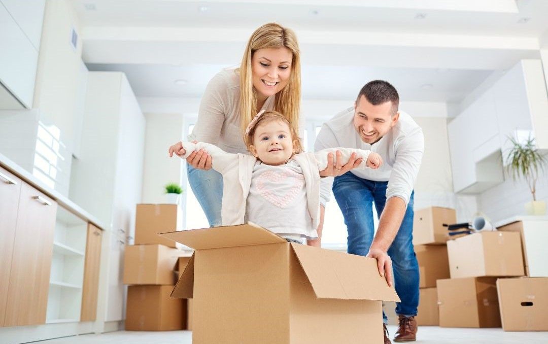 A family is playing with a baby in a cardboard box.
