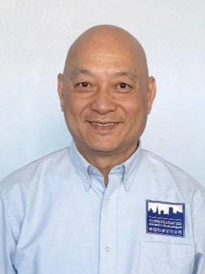 A bald man in a light blue shirt is smiling for the camera.