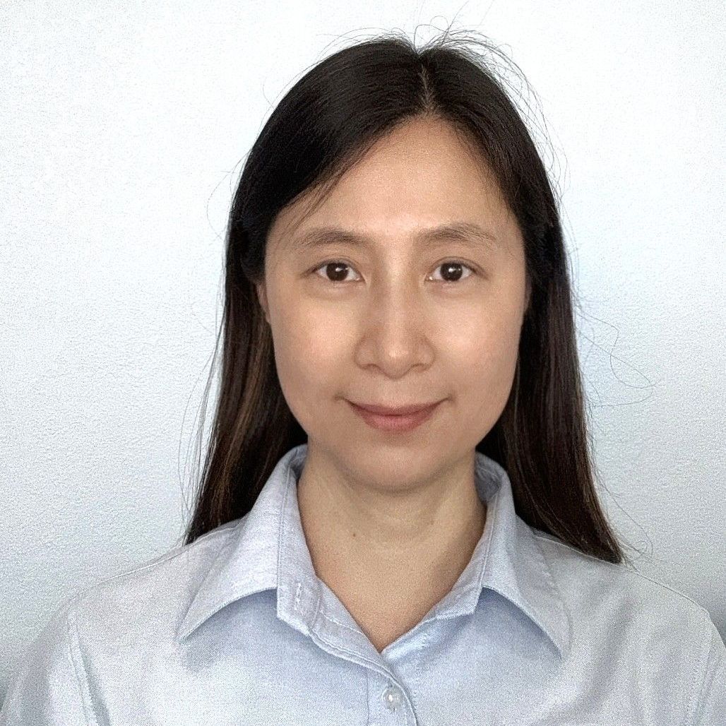 A woman with long hair is wearing a blue shirt and smiling for the camera.
