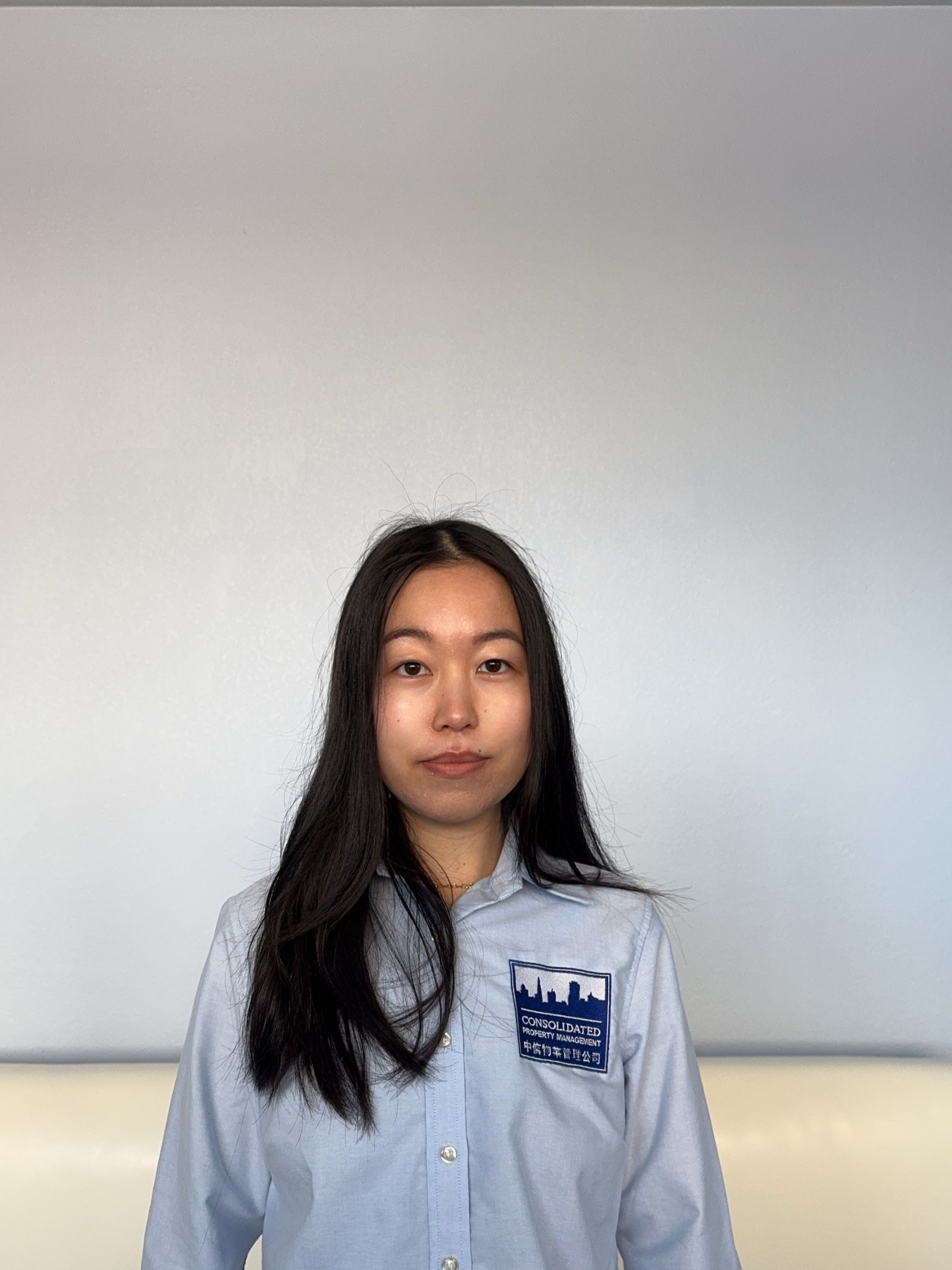 A young man wearing glasses and a grey shirt is looking at the camera.