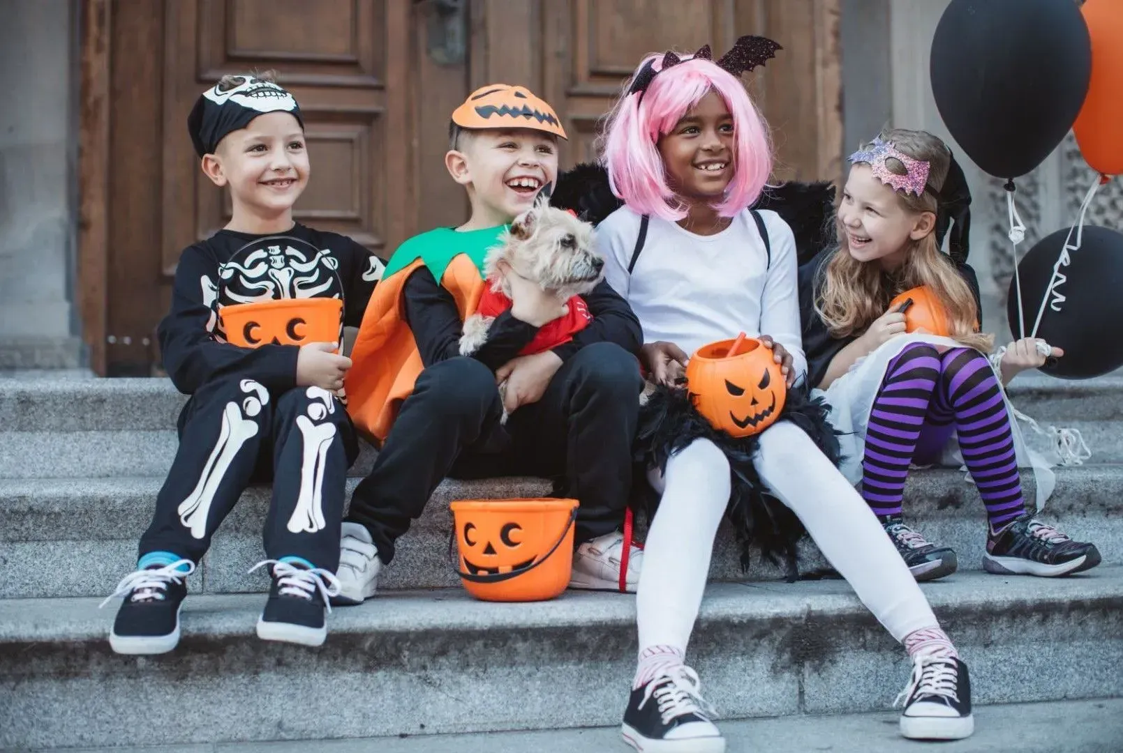 A group of children in halloween costumes are sitting on the steps of a building.