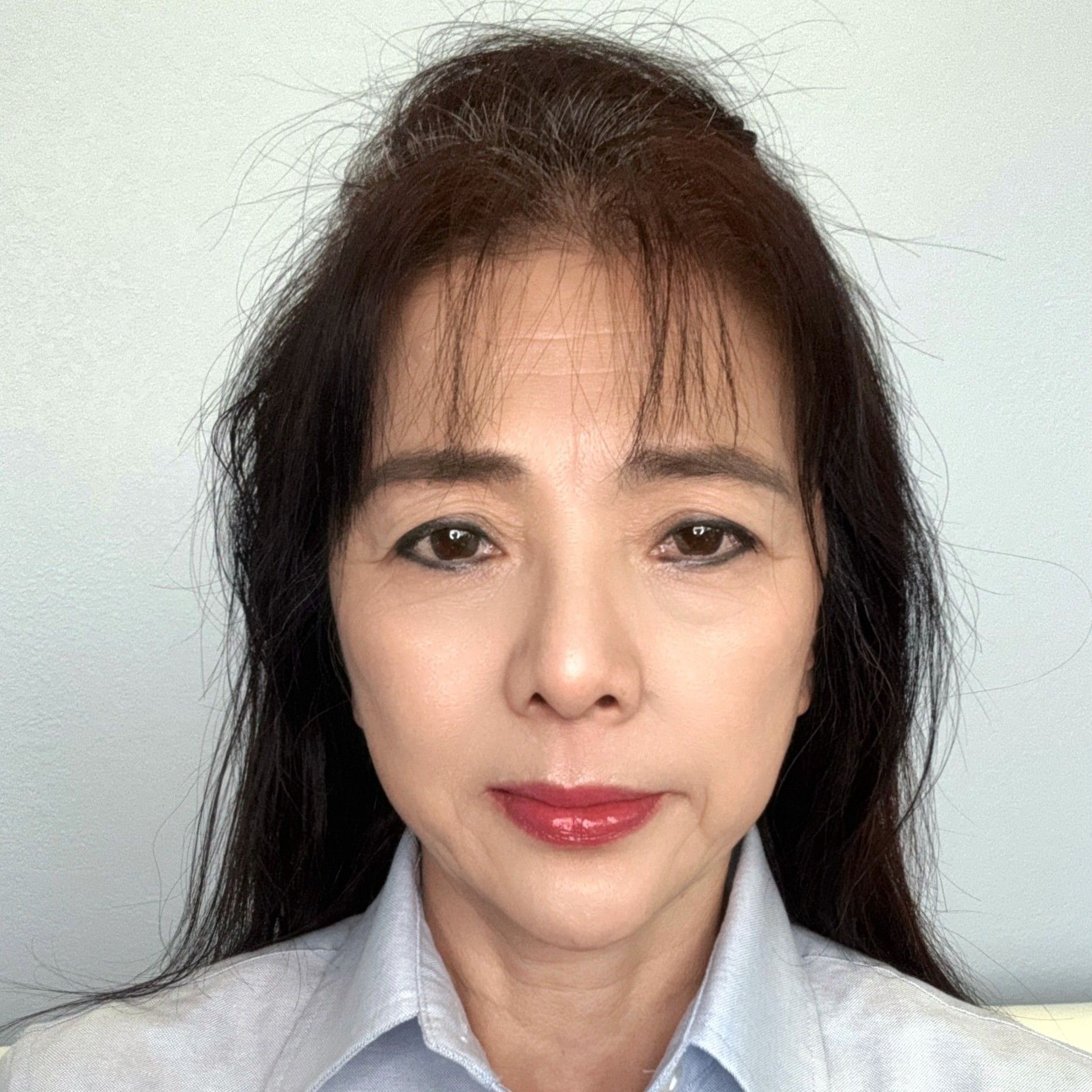 A close up of a woman 's face with long hair and a blue shirt.