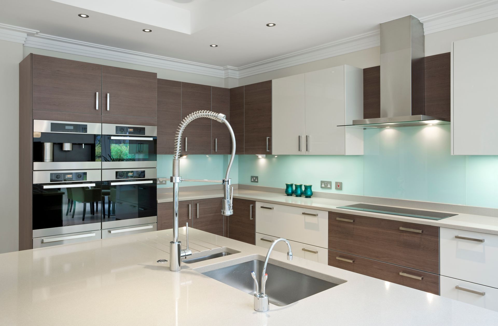 Modern kitchen with brown and white cabinets, stainless steel appliances, and a light blue backsplash.