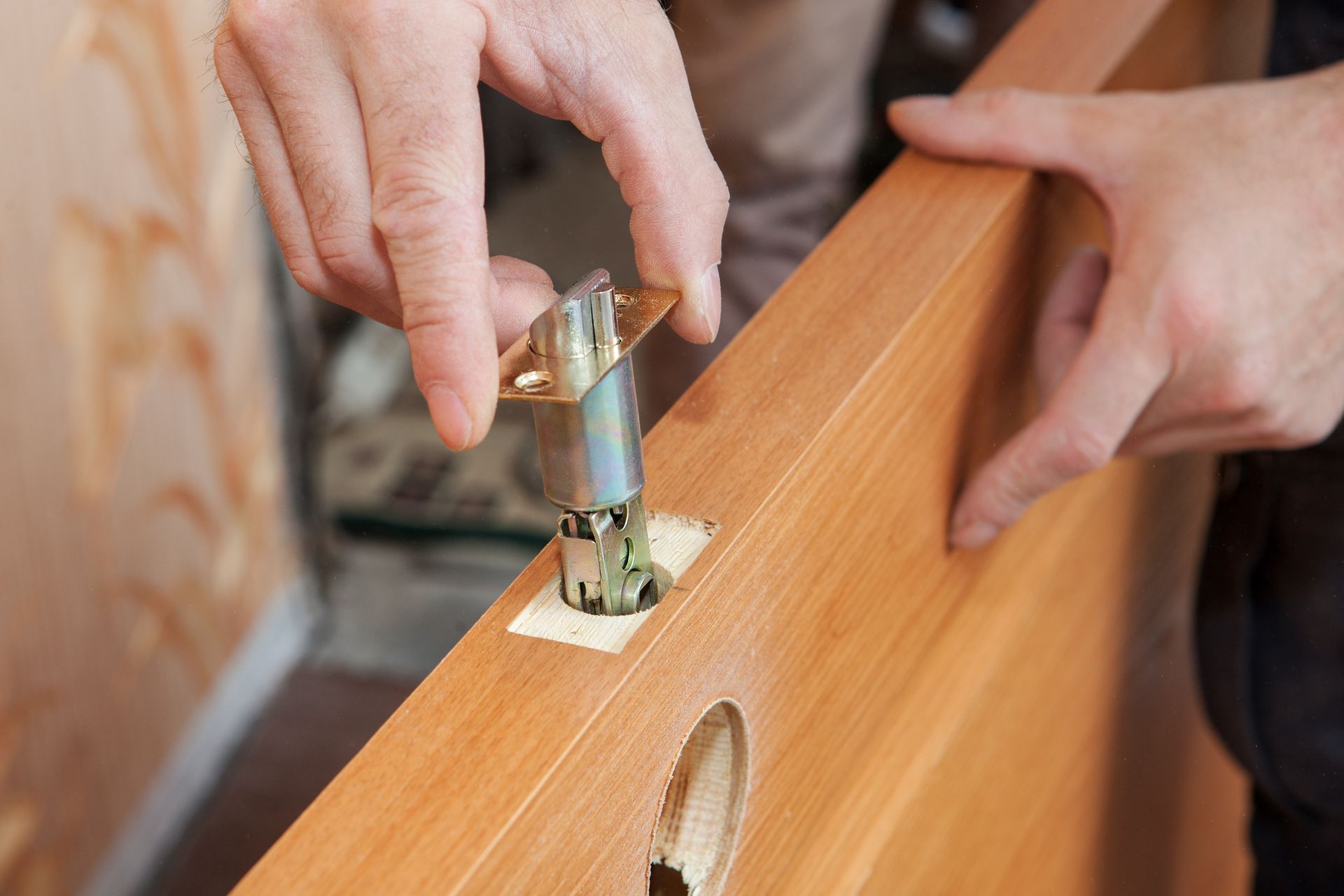 Person installing a door latch into a wooden door.