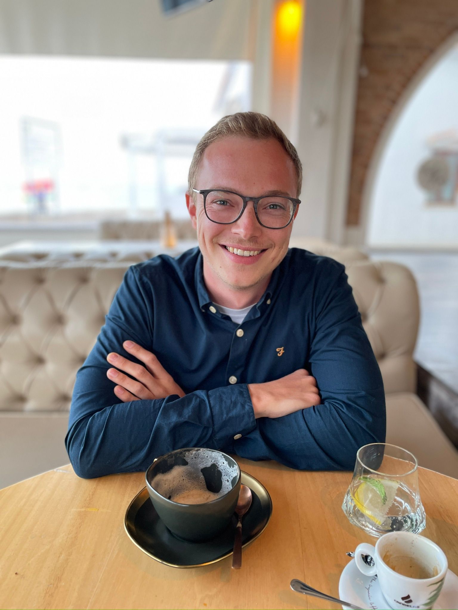 Ein Mann sitzt mit einer Tasse Kaffee und einer Schüssel Suppe an einem Tisch.