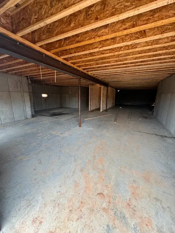 A basement under construction with a wooden ceiling and concrete floor.