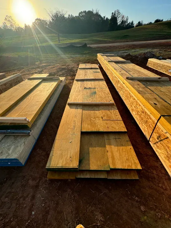A bunch of wooden boards are stacked on top of each other on the ground.
