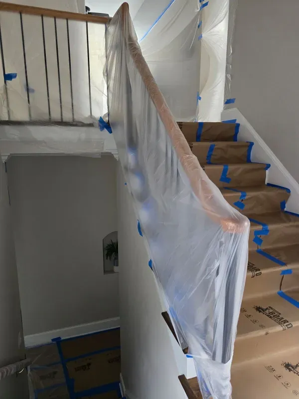 A staircase is being painted and covered in plastic