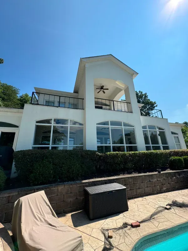 A large white house with a swimming pool in front of it.