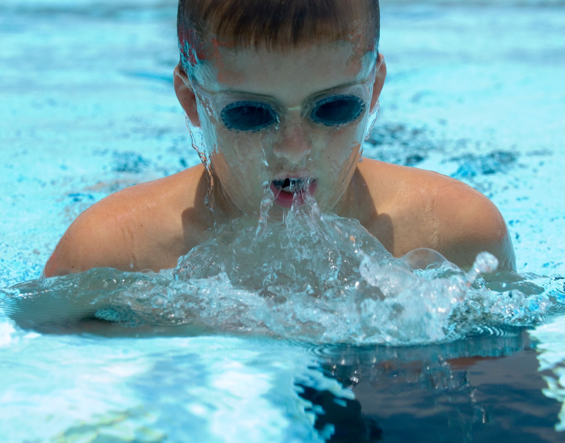 A young boy wearing goggles is swimming in a pool-Swim School In Valentine, NSW