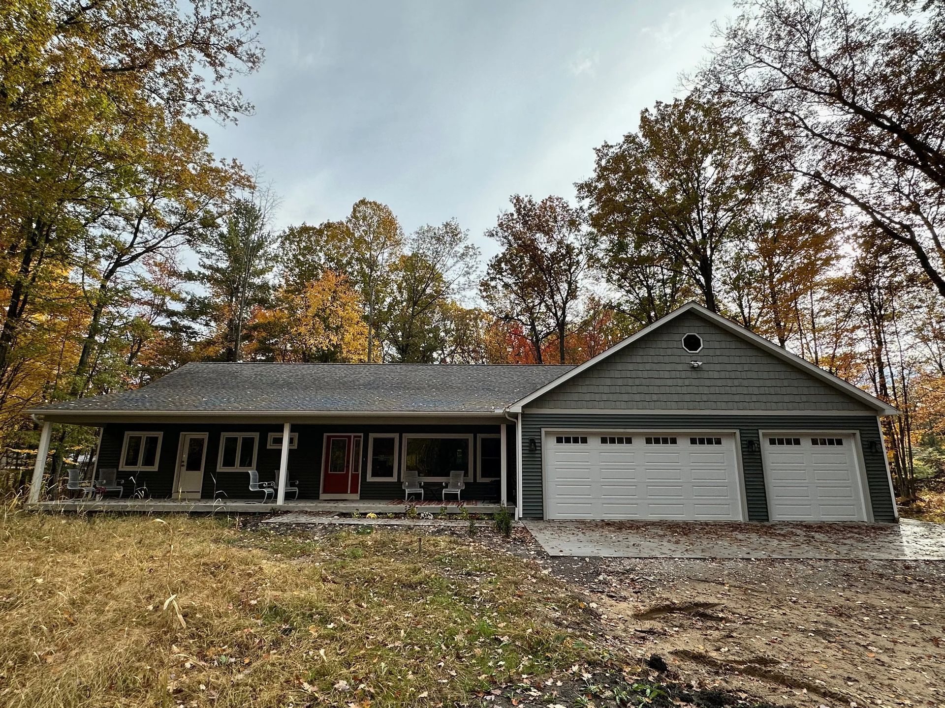 Single-story house with attached two-car garage, autumn trees, and a gravel driveway