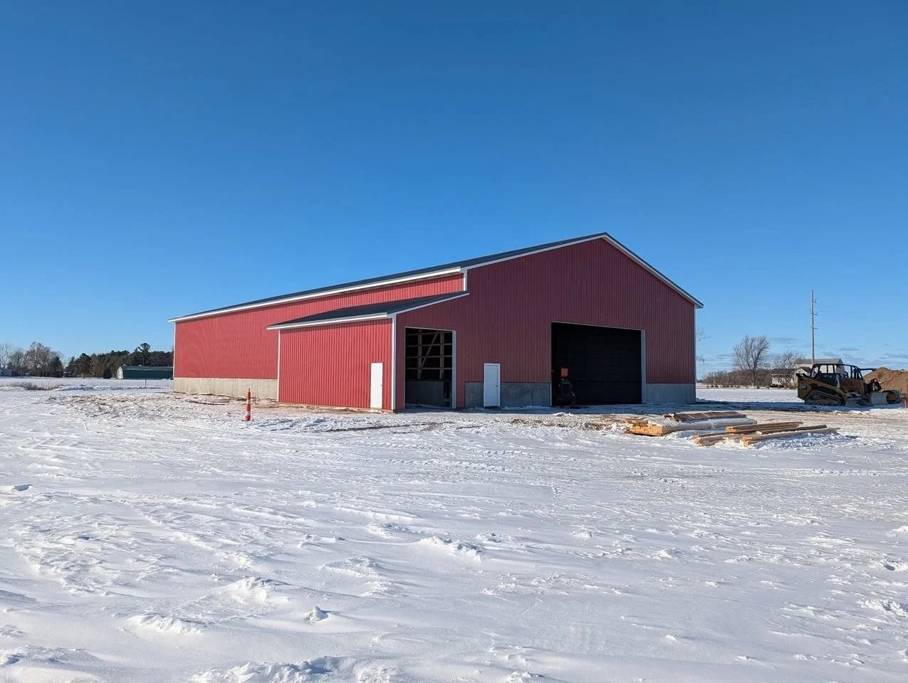 Red barn on a snowy field under a clear blue sky
