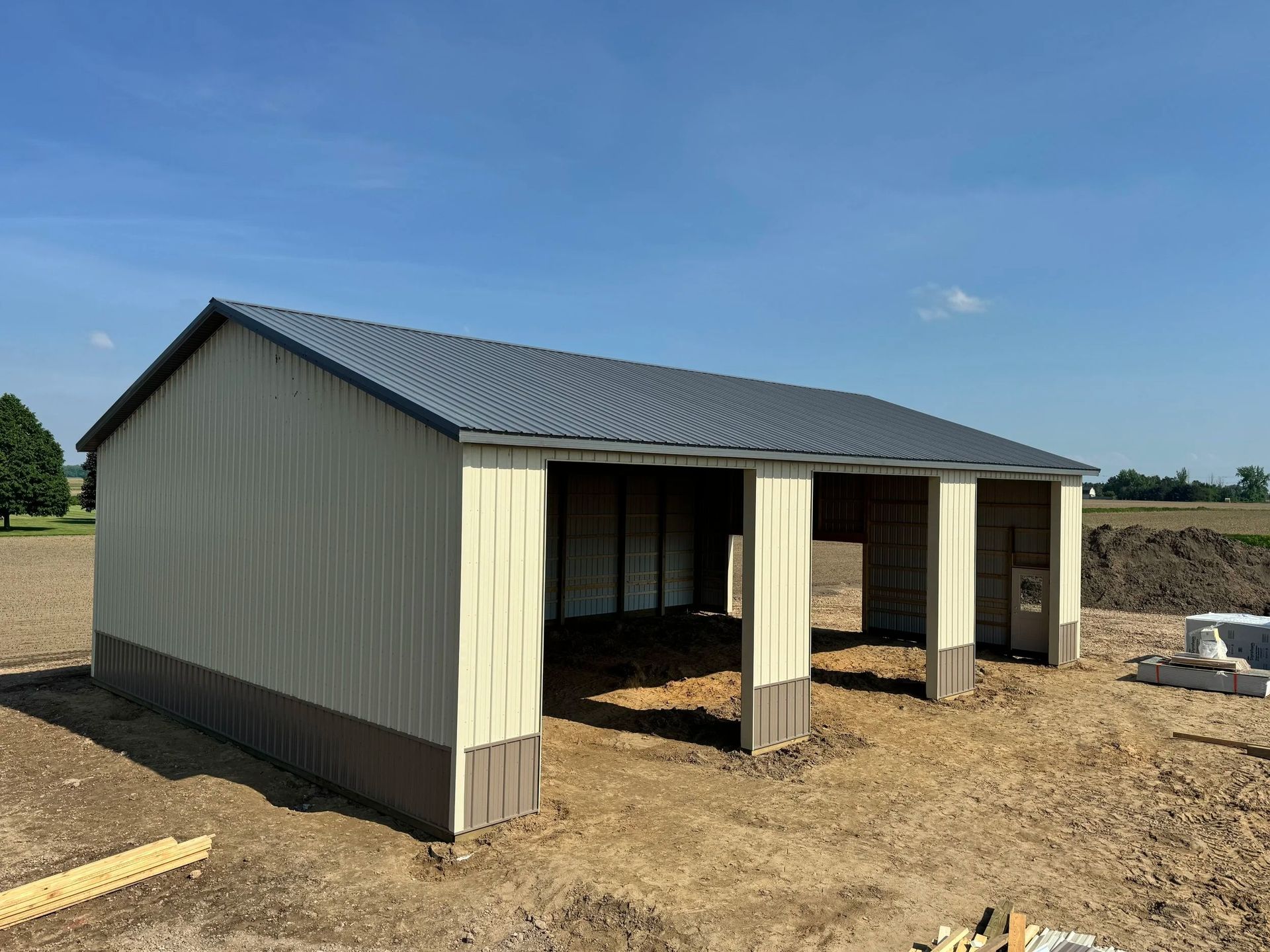 Small metal storage shed with open front bays on a dirt lot under a blue sky