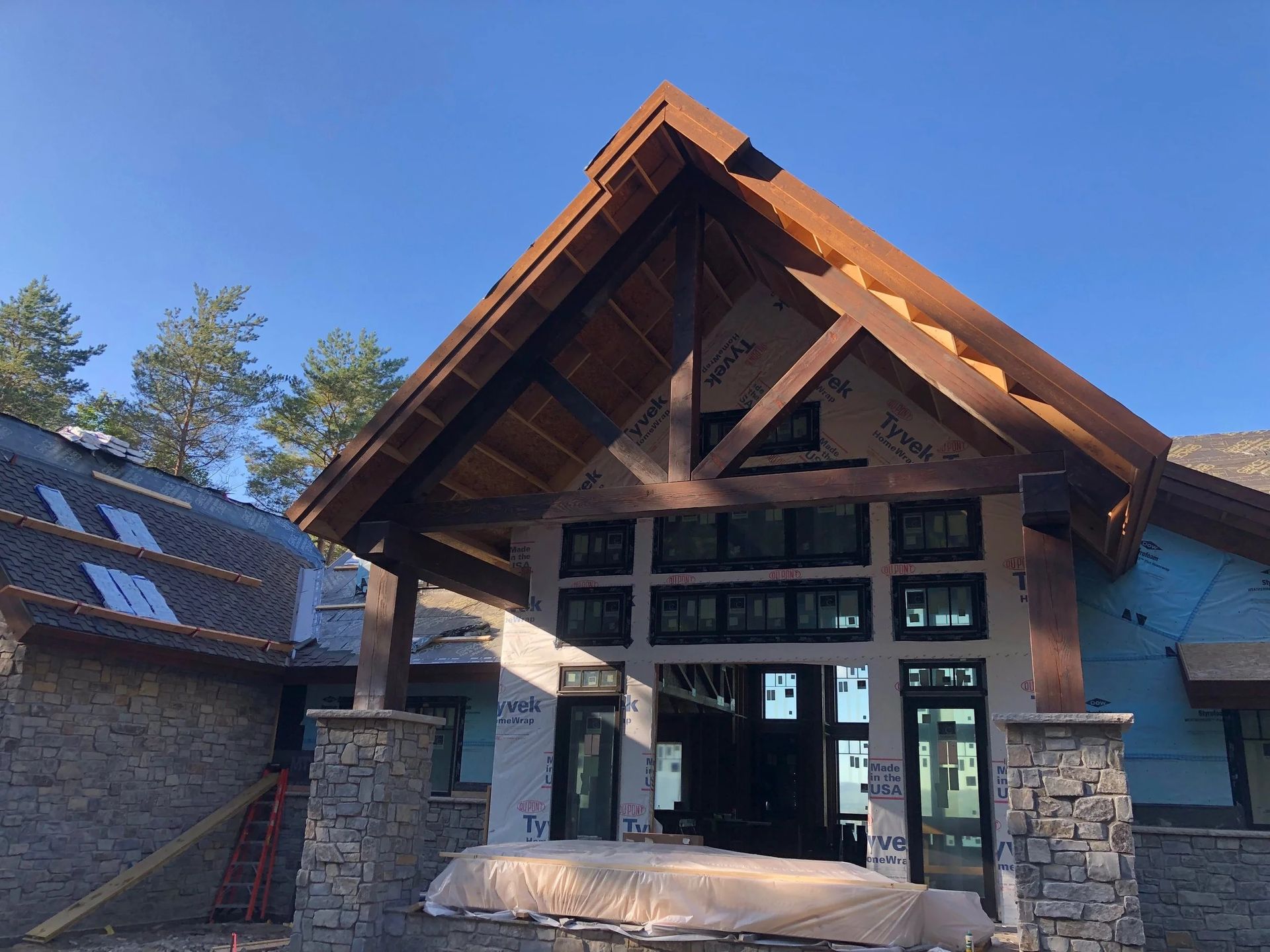 Rustic stone-and-wood building entrance with a peaked roof and large glass doors under a blue sky
