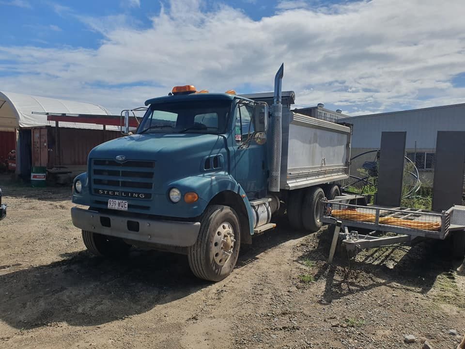 A Blue Dump Truck is Parked in a Dirt Lot Next to a Trailer — Advanced Civil Earthworks In Koah, QLD