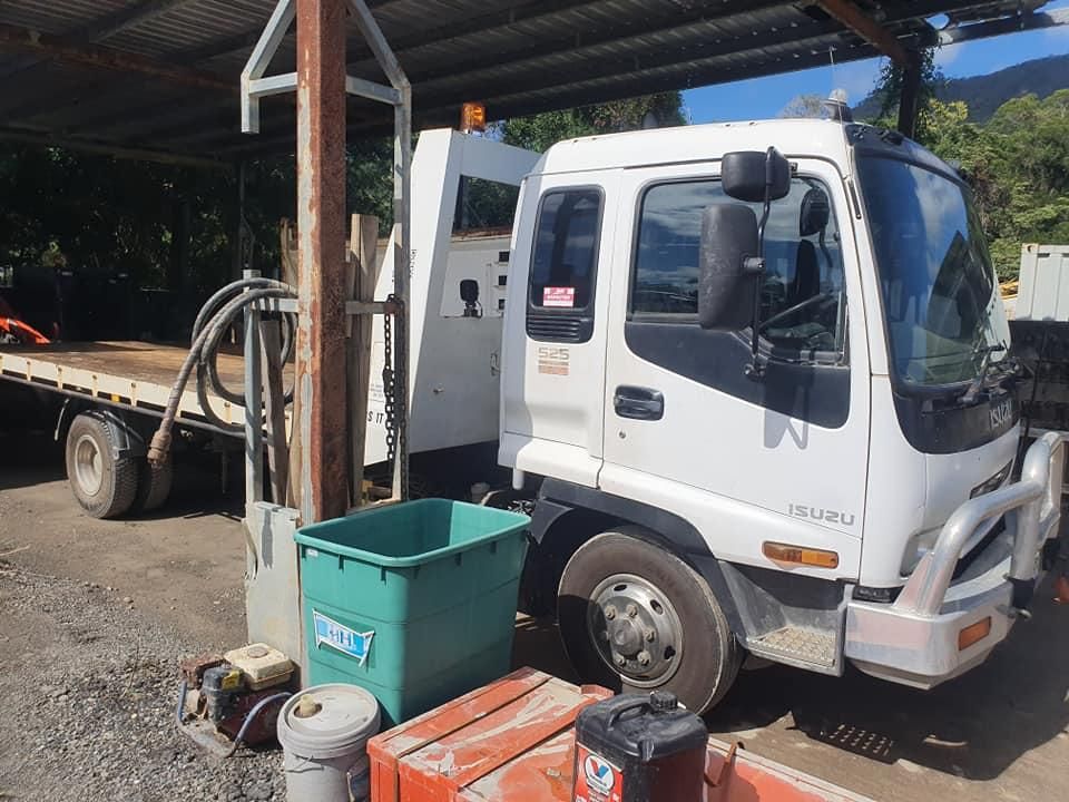 A White Flatbed Truck is Parked Under a Shed — Advanced Civil Earthworks In Cape York, QLD